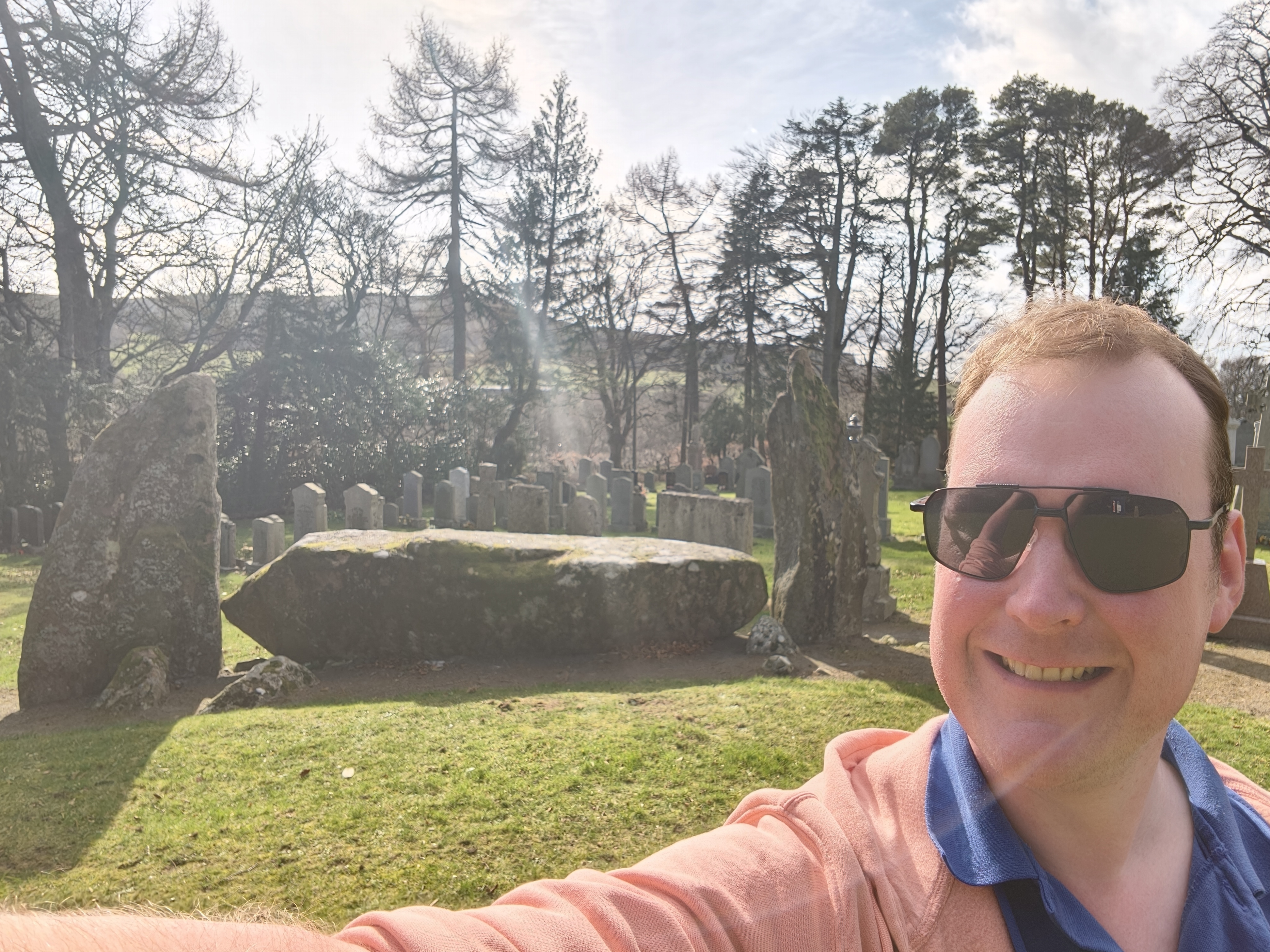 Jamie beside an ancient stone at a historic site