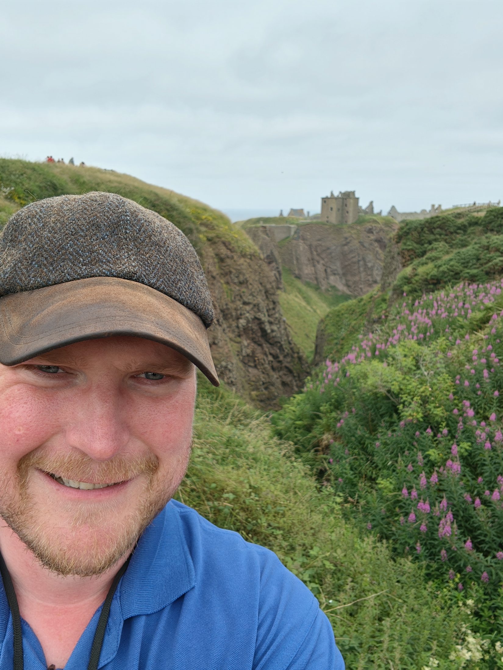 Jamie with Dunnottar Castle on the cliffs behind him